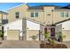 Tan three-story townhome with two-car garage, red door, and landscaping at 8879 Cabot Cliffs Dr # 103, Davenport, FL 33896