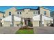 Tan three-story townhome with two-car garage, red door, and landscaping at 8879 Cabot Cliffs Dr # 103, Davenport, FL 33896