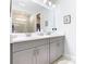 Double vanity bathroom with gray cabinets and a large mirror at 1062 Umbria Dr, Kissimmee, FL 34759