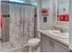 Cozy bathroom featuring a shower with patterned curtains, a vanity with storage, and decorative wall art at 2285 Palm Tree Dr, Kissimmee, FL 34759
