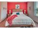 Cozy bedroom with a king-size bed, vibrant red accent wall, and bright natural light at 2285 Palm Tree Dr, Kissimmee, FL 34759