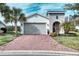 Curb appeal with gray garage door, landscaping, and brick driveway at 2285 Palm Tree Dr, Kissimmee, FL 34759