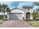 One-story home with gray garage door, landscaping, and brick driveway at 2285 Palm Tree Dr, Kissimmee, FL 34759