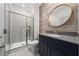Bathroom with gray tile shower, dark vanity, and round mirror at 2381 Reading Trl, Kissimmee, FL 34746