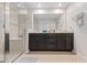 Bright bathroom featuring a glass-enclosed shower and a dark wood vanity with double sinks at 2449 Varenna Loop, Kissimmee, FL 34741