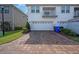 Townhouse featuring a brick paver driveway leading to a two-car garage and featuring an upstairs balcony at 2449 Varenna Loop, Kissimmee, FL 34741