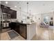 Modern kitchen featuring dark cabinets, stainless steel appliances, and an island with an extended countertop at 2449 Varenna Loop, Kissimmee, FL 34741