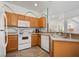 Corner kitchen showcases wood cabinetry, white appliances and stainless steel sink with green wall accents at 2818 Roccella Ct, Kissimmee, FL 34747
