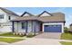 Craftsman style home with red door, blue garage, and a well manicured lawn at 3055 Prospect Trl, St Cloud, FL 34771