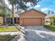 Tan house with screened porch, palm trees, and a paver driveway at 327 Davinci Pass, Kissimmee, FL 34759