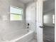 Bathtub with marble tile surround and window in a renovated bathroom at 438 Jay Ct, Kissimmee, FL 34759