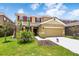 Two-story house with tan siding, red shutters, and a landscaped lawn at 7638 Oakmoss Loop, Davenport, FL 33837