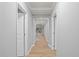 Well-lit hallway with wood flooring and doors leading to various rooms in the home at 7658 Whisper Way # 202, Reunion, FL 34747