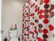 Bathroom with toilet and shower, featuring a red and white shower curtain at 1320 Moss Creek Ln, Davenport, FL 33836