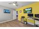 Bedroom with yellow accent wall, desk, and large TV at 1320 Moss Creek Ln, Davenport, FL 33836