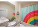 Colorful bathroom with a rainbow shower curtain, fresh white towels, and neutral-toned walls at 2797 Bookmark Dr, Kissimmee, FL 34746