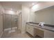Well-lit bathroom with a glass-enclosed shower, double vanity with gray countertops, and a large mirror at 2797 Bookmark Dr, Kissimmee, FL 34746
