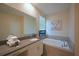 Bright bathroom with a soaking tub, TV, neutral stone tile surround, and a large vanity with a modern sink at 2797 Bookmark Dr, Kissimmee, FL 34746