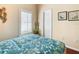 Bedroom with a teal floral comforter, window with plantation shutters, and wood floors at 301 Anastasia Dr, Kissimmee, FL 34759