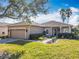Tan one-story house with landscaping, driveway, and two-car garage at 301 Anastasia Dr, Kissimmee, FL 34759