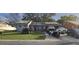 Single story home with solar panels, well-manicured lawn, and multiple vehicles in driveway at 372 La Paz Dr, Kissimmee, FL 34743