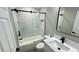 Modern bathroom featuring a tub with sliding glass doors and a bright white vanity with black hardware at 3839 Se 132Nd Pl, Belleview, FL 34420