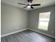 This bedroom has wood-look flooring, a ceiling fan, and a window providing bright, natural light at 3839 Se 132Nd Pl, Belleview, FL 34420
