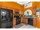 Kitchen boasts wood cabinets, black appliances, and orange colored walls at 8077 Roaring Creek Ct, Kissimmee, FL 34747