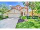 Two-story house with a beige exterior, two-car garage, and manicured lawn at 5192 Oakbourne Ave, Davenport, FL 33837
