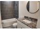 Modern bathroom with a granite countertop, a round mirror and tiled shower at 1321 Congo Dr, Kissimmee, FL 34759