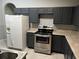 Kitchen featuring white refrigerator, stainless steel range, gray cabinets, and tile floors at 228 Remington Pl, Haines City, FL 33844