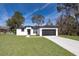 White house with black accents, concrete driveway, and grassy lawn at 4411 Sw 132Nd Pl, Ocala, FL 34473