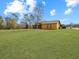 Back exterior of a house showing a large grassy yard, a screened porch, and trees at 713 Green Ct, Kissimmee, FL 34759