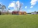 Backyard view of a home showcasing a large grassy area and mature trees at 713 Green Ct, Kissimmee, FL 34759