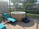 Outdoor jacuzzi with lounge chair sitting on brick patio with protective screen, next to a lush grassy yard and neighborhood at 9158 Scramble Dr, Davenport, FL 33896