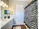Neutral bathroom with double sinks, modern lighting and a bathtub with a black-and-white shower curtain at 127 Terra Vista Ln, Kissimmee, FL 34759