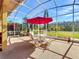 Screened lanai with outdoor seating area and red umbrella, offering beautiful views at 127 Terra Vista Ln, Kissimmee, FL 34759