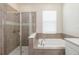 Elegant bathroom featuring a glass-enclosed shower and a luxurious soaking tub by a bright window at 1813 Castleton Dr, St Cloud, FL 34771