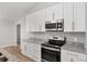 Well-lit kitchen features stainless steel appliances, modern white cabinets, and granite countertops at 4181 Sw 111Th Pl, Ocala, FL 34476