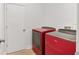 A dedicated laundry room featuring red Whirlpool washer and dryer appliances next to a door at 4181 Sw 111Th Pl, Ocala, FL 34476