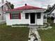 View of a small house with a red metal roof and a well-manicured yard at 433 Pennsylvania Ave, St Cloud, FL 34769