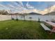 Spacious backyard with a grassy lawn, wooden picnic table, and a white fence at 4702 Greycliff Prairie Dr, Kissimmee, FL 34758