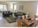 Open living and dining area with gray sofas, wooden dining table, and tiled floors at 5465 Misty Oak Cir, Davenport, FL 33837