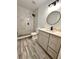 Modern bathroom with gray vanity, marble shower, and round mirror at 656 Oakford Way, Orlando, FL 32811