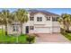 Two-story house with beige exterior, brick driveway, and palm trees at 2821 Rialto Ct, Kissimmee, FL 34746