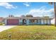 Light blue house with red garage door and a manicured lawn at 508 Bar Dr, Kissimmee, FL 34759