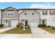 Two-story townhome with gray siding, white garage door, and landscaping at 592 Madison Dr, Davenport, FL 33837