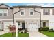 Two-story townhome with gray siding, white garage doors, and landscaping at 592 Madison Dr, Davenport, FL 33837