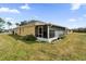 Wide backyard view, showcases the screened-in lanai, well-maintained lawn, and exterior of the light yellow home at 760 Lake Marion Golf Resort, Poinciana, FL 34759
