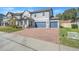 Two-story house with a gray exterior, blue garage doors, and a brick driveway at 2230 Standing Rock Cir, Oakland, FL 34787